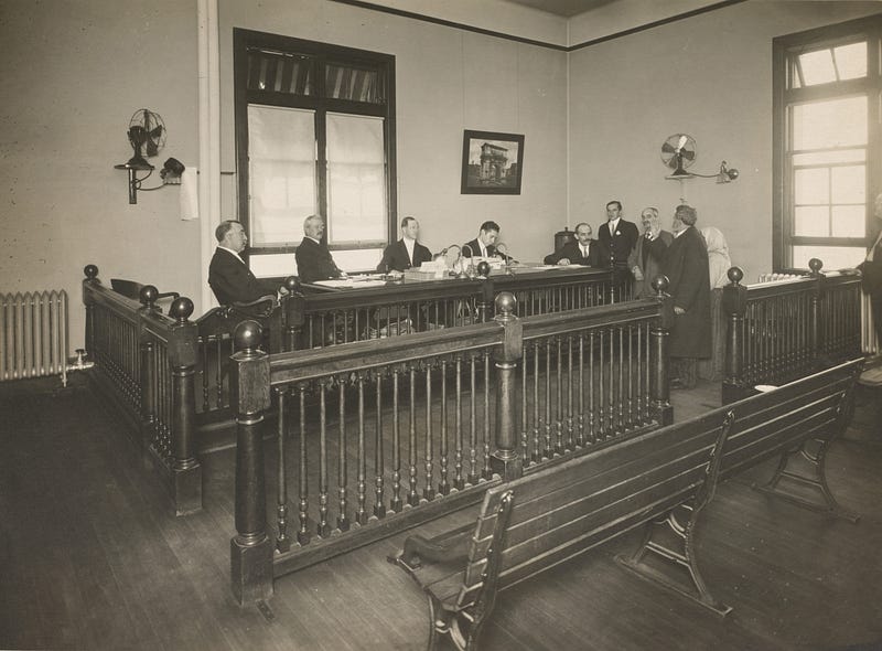 An old court room scene with several lawyers appearing before a judge.