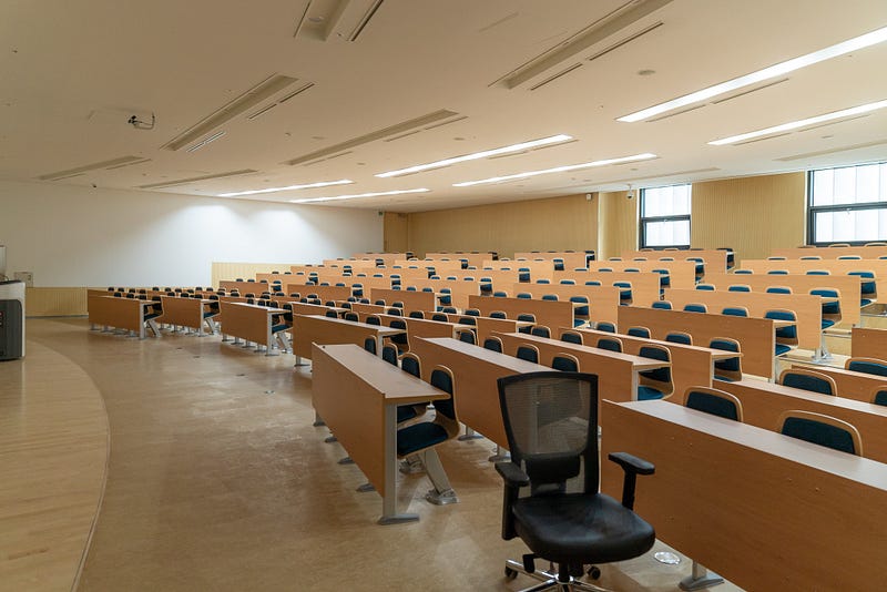 An empty university lecture room large enough for 100 students.  The lights are on waiting for the students to arrive.
