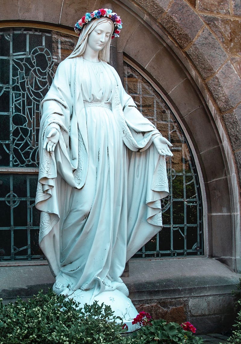 Saint Mary, with a crown of flowers, her hands are held open to welcome the lord.